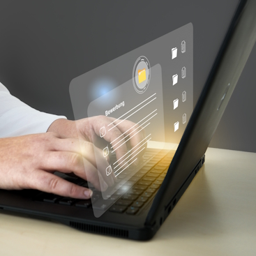 Person mit Laptop und transparenter Benutzeroberfläche. Person arbeitet am Laptop. Die Hände sind auf der Tastatur. Man sieht eine virtuelle Oberfläche.